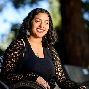 Daniela sits on a park bench smiling