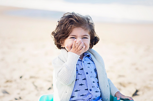 Julian, age 2 smiles on a beach 