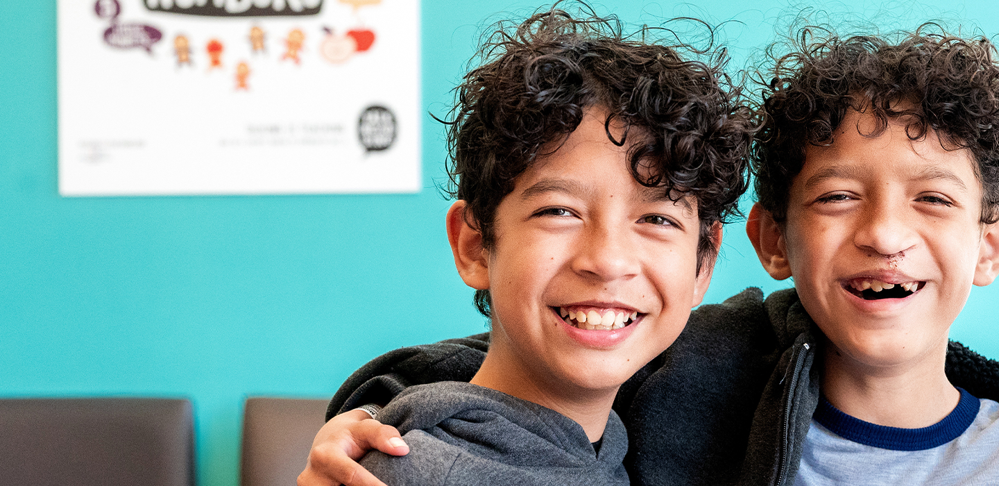 Twin brothers smile at the camera.