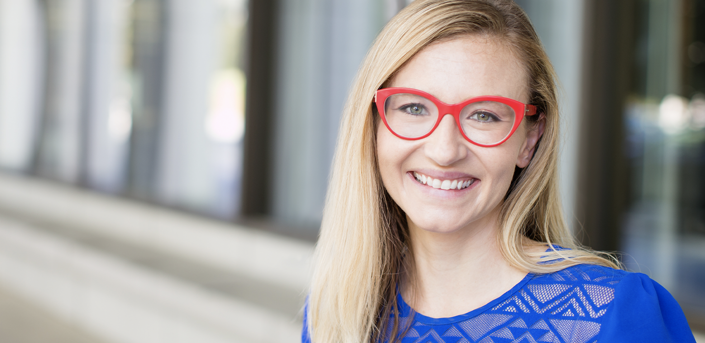 Mary smiling in her red glasses and blue shirt