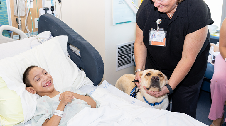 a patient smiles with a facility dog
