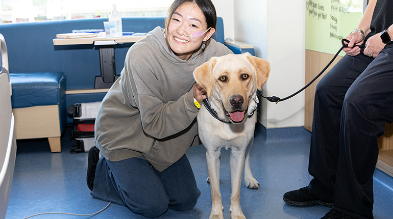 a teen patient smiles with a facility dog 