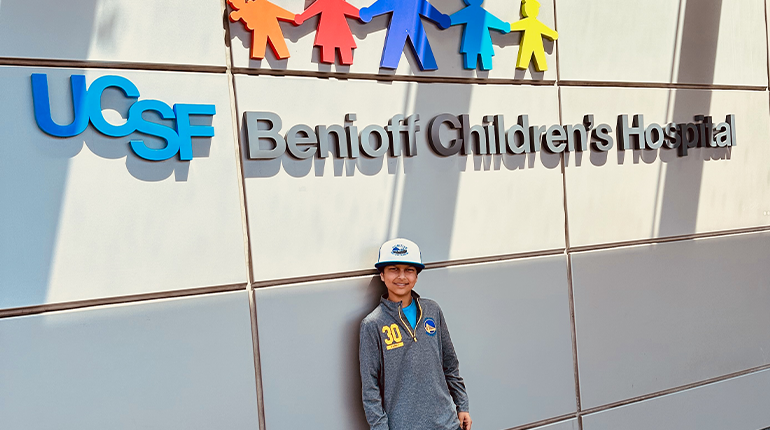 Tej outside of UCSF Benioff Children's Hospital Mission Bay during cancer treatment.